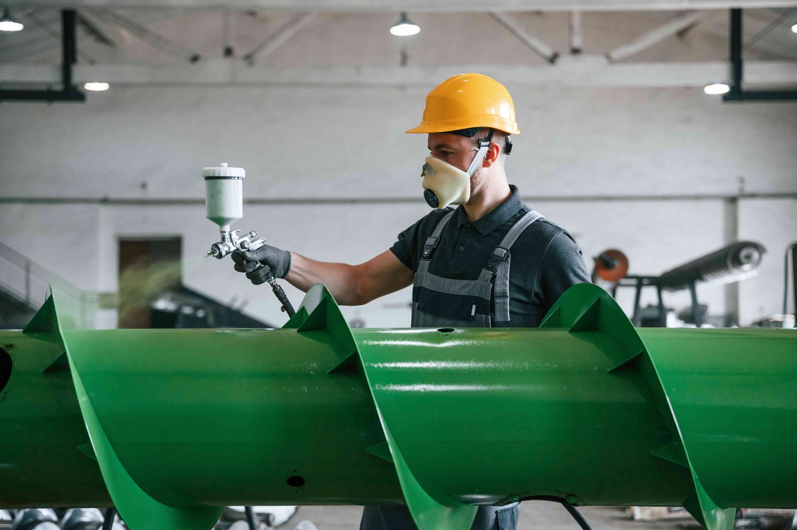 a man in uniform is in workstation painting an agriculture equipment
