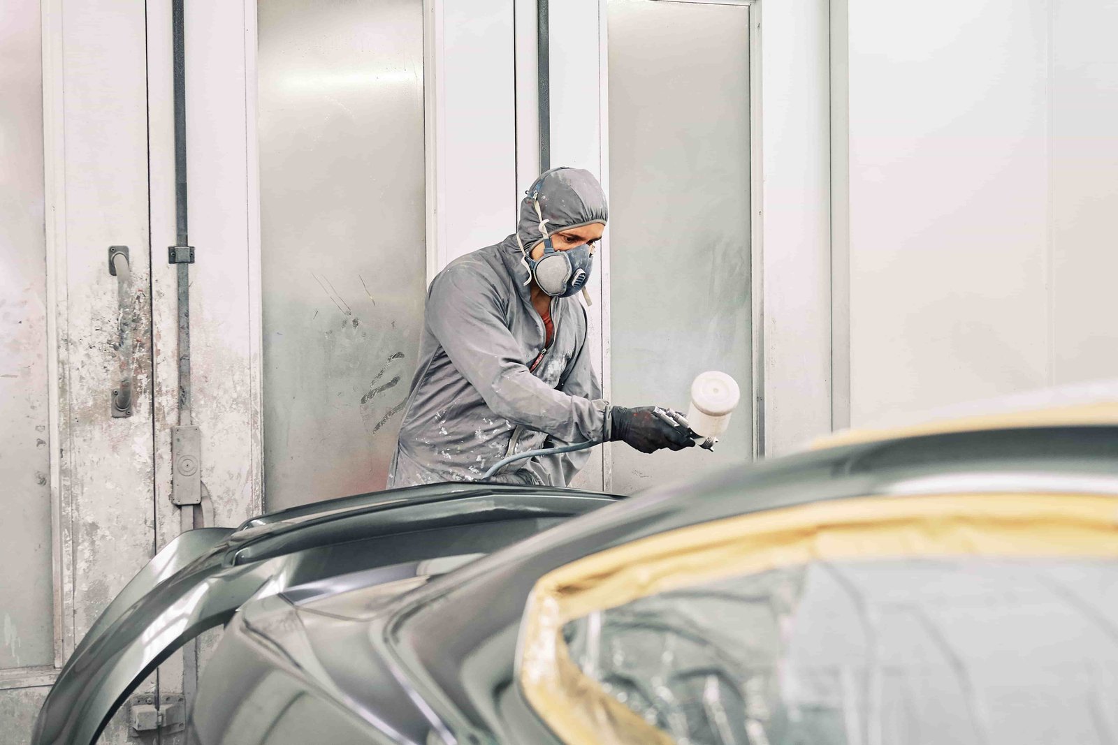 a man painitng a car in a workshop